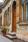 Steinpflaster und kleine Haustür in der Nähe der Fassade eines in die Jahre gekommenen schmuddeligen Gebäudes an der Straße einer kleinen Stadt — Stockfoto