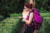 Donna in piedi in cespugli verdi nel parco con bussola in mano — Foto stock