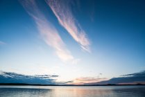 Поверхня спокійного блакитного озера з драматичним небом на заході сонця — стокове фото