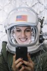 Female astronaut in illuminated vintage helmet with mobile phone — Stock Photo
