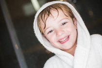 Portrait of smiling little boy with wet hair in bathrobe — Stock Photo