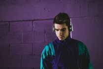 Молодой человек в спортивной одежде слушает музыку в наушниках — стоковое фото
