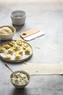 Тесто и миска творога во время приготовления тортеллини на сером столе — стоковое фото