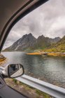 Paesaggio di alte montagne belle vicino ondulazione fiume sotto cielo nuvoloso attraverso la finestra di auto in movimento — Foto stock
