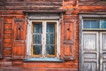 Janela pequena com persianas e porta rasgada da antiga casa de madeira — Fotografia de Stock