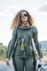 Astronauta femenina con pelo rizado caminando por la carretera en la naturaleza - foto de stock