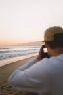 Мужчина с фотоаппаратом стоит на пляже — стоковое фото