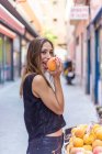 Весела жінка кусає персик на ринку — стокове фото