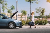 Mädchen verlässt kaputtes Auto mit Gepäck — Stockfoto