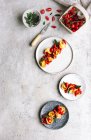 Piatti di tortellini serviti con pomodori su tavolo grigio — Foto stock