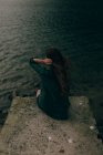 Молода жінка сидить на скелі біля озера — стокове фото