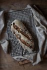 Буханка вкусного ржаного хлеба с клюквой и грецкими орехами на решетке на деревянном столе — стоковое фото