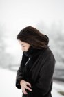 Vista lateral de la joven hembra en ropa de abrigo caminando cerca de la cerca en el ventoso día de invierno en el magnífico campo - foto de stock