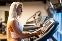 Blonde junge Frau trainiert auf Laufband — Stockfoto