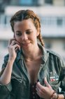 Porträt einer rothaarigen jungen Frau mit Zöpfen, die im Freien mit dem Handy spricht — Stockfoto