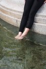 Nahaufnahme weiblicher Beine in schwarzen Strumpfhosen in transparentem ruhigem Wasser — Stockfoto
