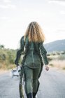 Vista posteriore della donna che indossa costume da astronauta a piedi lungo la strada di campagna — Foto stock