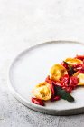 Смачна страва тортелліні з помідорами, поданими на тарілці на сірій тарілці — стокове фото