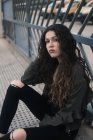 Young brunette sitting on metal path — Stock Photo