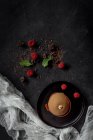 Chocolate con frambuesas rojas, menta y pastel sobre fondo oscuro - foto de stock