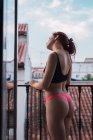 Young woman in lingerie standing at balcony with view of old city roofs — Stock Photo