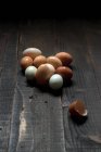 Купа білих і коричневих яєць з мокрою оболонкою на темному дерев'яному столі — стокове фото