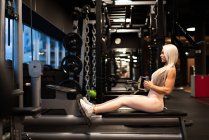 Athletic young blond woman doing exercise on training equipment — Stock Photo