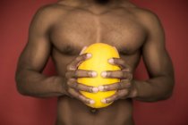 Gesichtslose Aufnahme eines muskulösen afrikanisch-amerikanischen Mannes, der ohne Hemd dasteht und Wassermelone in der Hand hält — Stockfoto
