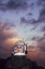 Ragazza che indossa il vecchio casco spaziale e tuta spaziale contro il cielo drammatico al tramonto — Foto stock