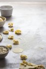 Dough and bowl of cottage cheese while preparing tortellini on grey tabletop — Stock Photo