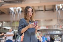 Mujer usando smartphone en estación de tren - foto de stock