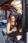 Donna con drink e smartphone vicino al caffè all'aperto — Foto stock