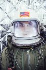 Chica con casco espacial viejo con bandera americana signo y traje espacial contra fondo de aluminio - foto de stock