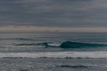 Grandes olas bajo el cielo nublado - foto de stock