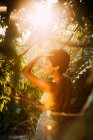Vista lateral de atractiva hembra joven en topless posando en el jardín - foto de stock