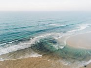Playa de arena bañada por agua de mar - foto de stock