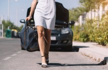 Mädchen verlässt kaputtes Auto mit Gepäck — Stockfoto