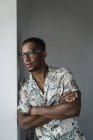 Casual black man leaning on white wall near window and thinking — Stock Photo