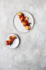 Delicioso plato de tortellini con tomates en platos sobre mesa gris - foto de stock
