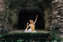 Tranquil woman doing yoga near stone cave — Stock Photo