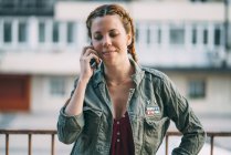 Porträt einer rothaarigen jungen Frau mit Zöpfen, die im Freien mit dem Handy spricht — Stockfoto