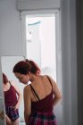 Вдумлива молода жінка стоїть перед дзеркалом — стокове фото