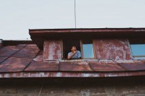 Знизу вибитий чоловік дивиться у вікно вивітрені котеджі в маленькому поселенні в Болгарії (Балкани). — стокове фото