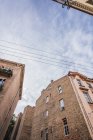 Brick buildings and electric wires against cloudy sky in old city — Stock Photo
