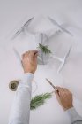 Männerhände dekorieren eingewickelte Drohne als Weihnachtsgeschenk mit Tannenzweig und Bindfaden auf weißem Hintergrund — Stockfoto
