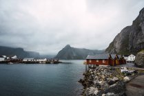 Quay with wooden houses on rocky sea coast in mountains — Stock Photo