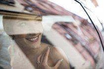 Улыбающаяся невеста смотрит на жениха из машины — стоковое фото