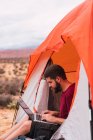 Путешественник с ноутбуком в палатке — стоковое фото