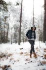 Bastante joven hembra en traje elegante mirando hacia otro lado mientras está de pie cerca del árbol cubierto de nieve en el día frío en el maravilloso campo - foto de stock