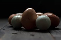 Белые и коричневые яйца с влажной скорлупой на темном деревянном столе — стоковое фото